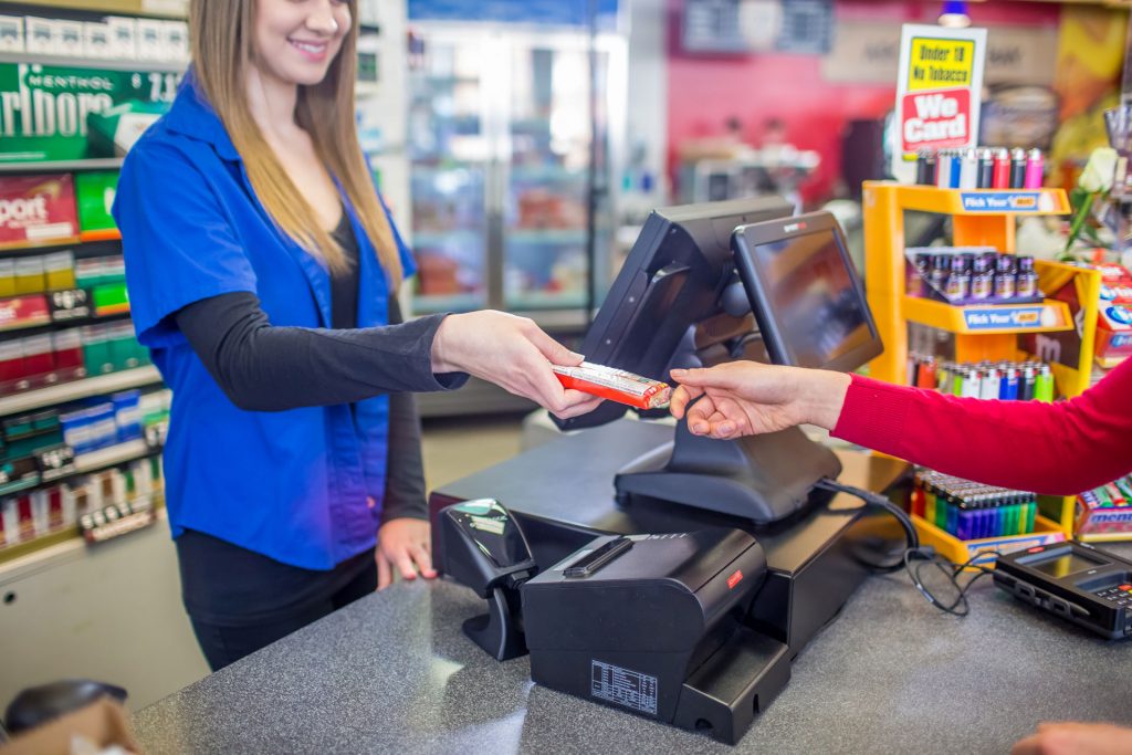 Smiling cashier handing item to customer