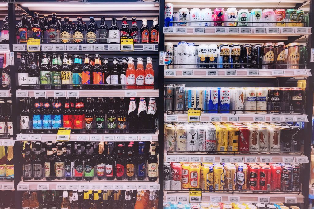 A cooler at a convenience store holds a variety of cans and bottles of beer. 